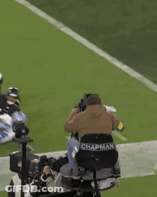 A Cameraman With Chapman Written On The Back Of His Seat GIF