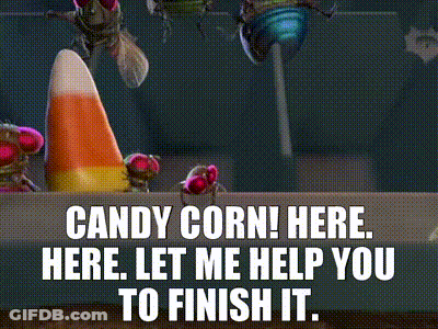 A Candy Corn Cone Is Sitting On A Table Next To A Bag Of Candy . GIF