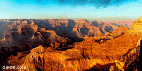 A Canyon With A Blue Sky And A Few Clouds GIF