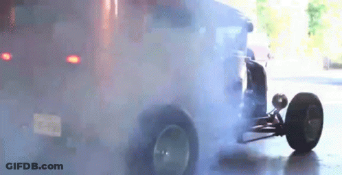 A Car Is Doing A Burnout In A Garage With Smoke Coming Out Of The Tires . GIF