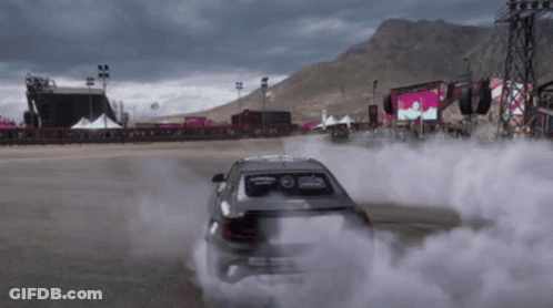 A Car Is Drifting On A Race Track With Smoke Coming Out Of It GIF