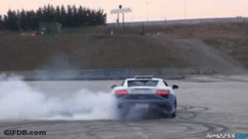 A Car Is Drifting On A Track With Smoke Coming Out Of The Exhaust Pipe GIF