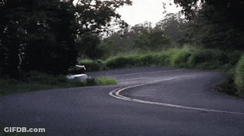 A Car Is Driving Down A Curvy Road In The Countryside GIF