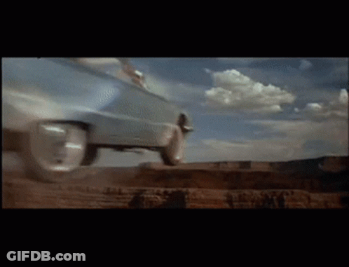 A Car Is Driving Down A Dirt Road With Clouds In The Background GIF