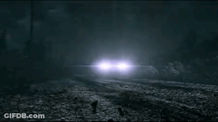 A Car Is Driving Down A Foggy Road At Night In The Woods . GIF