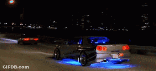 A Car Is Driving Down A Highway At Night And Has Blue Lights On The Tires GIF