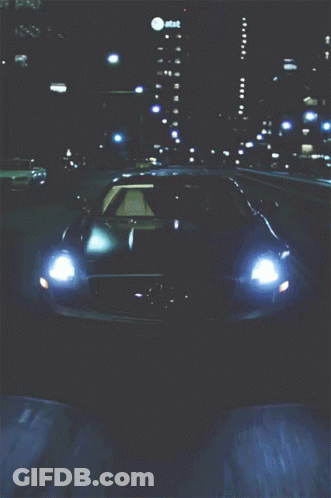 A Car Is Driving Down A Highway At Night With An At & T Building Behind It GIF
