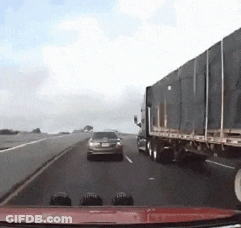 A Car Is Driving Down A Highway Next To A Truck GIF