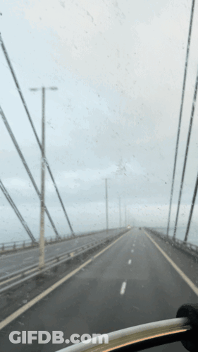 A Car Is Driving Down A Highway With A Gray Sky In The Background GIF