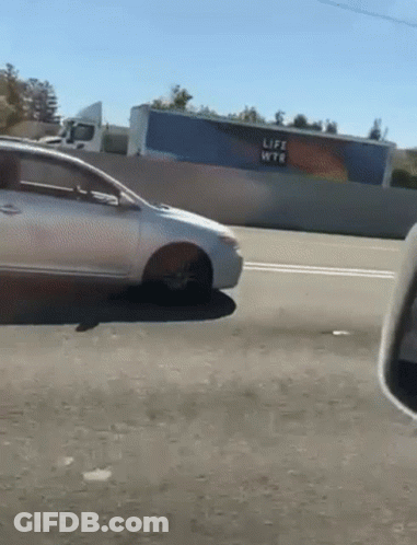 A Car Is Driving Down A Highway With A Life Wtr Sign In The Background GIF