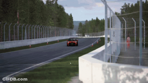 A Car Is Driving Down A Race Track With A Fence Around It GIF