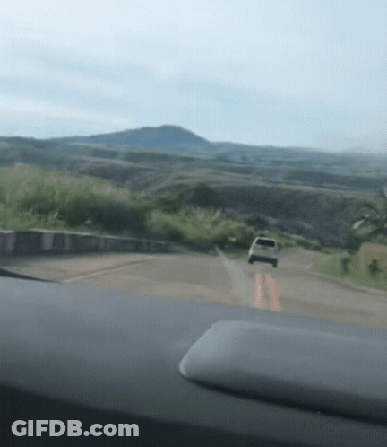 A Car Is Driving Down A Road In The Mountains GIF