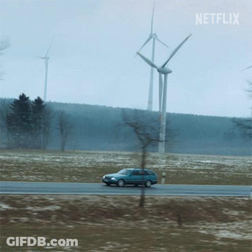 A Car Is Driving Down A Road With Windmills In The Background And A Netflix Logo GIF