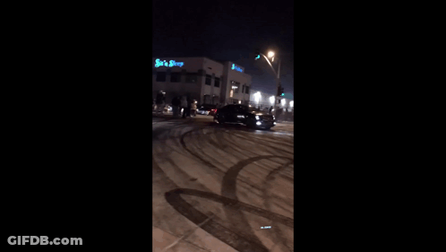 A Car Is Driving Down A Snowy Road At Night GIF