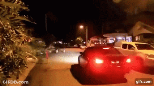 A Car Is Driving Down A Street At Night With A Red Tail Light GIF