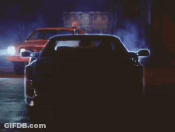 A Car Is Driving Down A Street At Night With The Lights On GIF