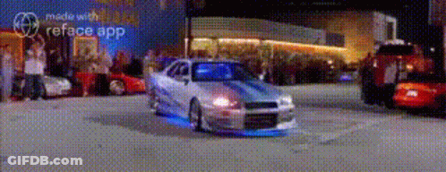 A Car Is Driving Down A Street In Front Of A Crowd Of People . GIF