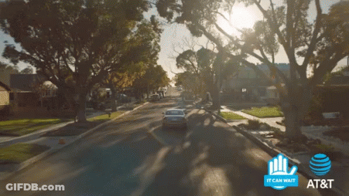 A Car Is Driving Down A Street Next To A Sign That Says It Can Wait GIF