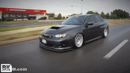 A Car Is Driving Down A Street With A Bk Logo On The Bottom Right GIF