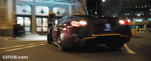 A Car Is Driving Down A Street With A Building In The Background That Has A Sign That Says No Parking GIF