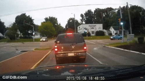A Car Is Driving Down A Street With A Sign That Says Williams Plaza GIF
