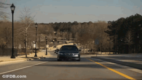 A Car Is Driving Down A Street With A Yellow Line GIF