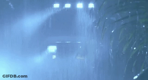 A Car Is Driving Through The Rain In The Dark . GIF
