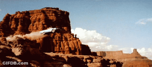 A Car Is Flying Through The Air On Top Of A Rocky Cliff GIF