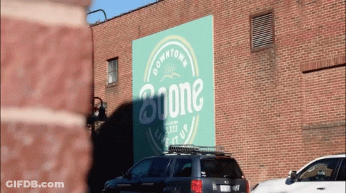 A Car Is Parked In Front Of A Building That Says Boone GIF