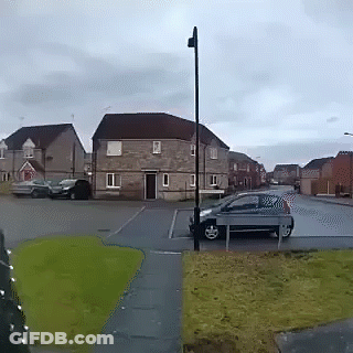 A Car Is Parked On The Side Of The Road In Front Of A Brick House GIF