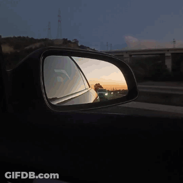 A Car Is Reflected In A Side View Mirror At Sunset GIF