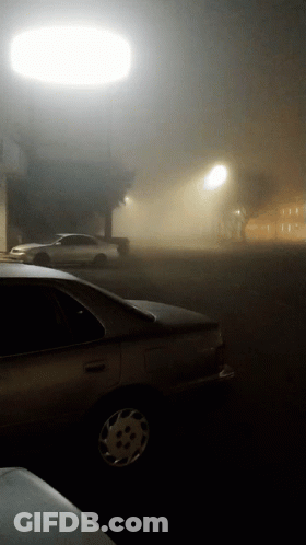 A Car Parked In A Foggy Parking Lot At Night GIF