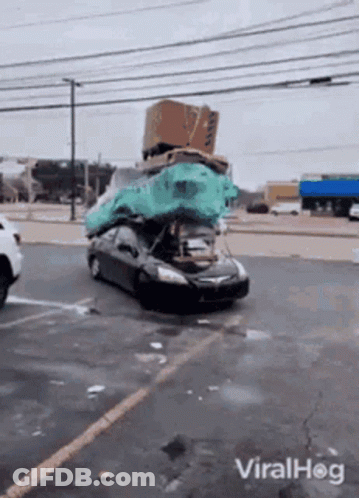 A Car With A Bunch Of Boxes On Top Of It In A Parking Lot GIF