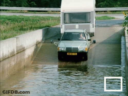 A Car With A License Plate That Says ' Hk-973-Tf ' Is Driving Through A Flooded Road GIF