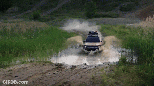 A Car With A Roof Rack Is Driving Through A Puddle GIF