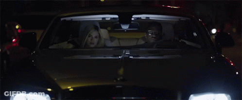 A Car With The Headlights On Is Driving Down A Street At Night GIF