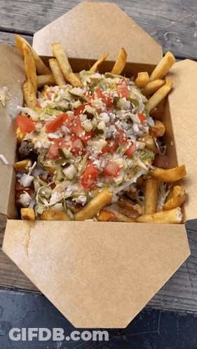 A Cardboard Box Filled With French Fries And Vegetables GIF