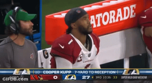 A Cardinals Football Player Sits In The Dugout With A Gatorade Sign In The Background GIF