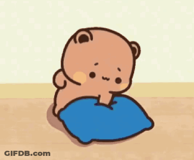 A Cartoon Bear Is Sitting On A Blue Pillow On A Wooden Floor . GIF