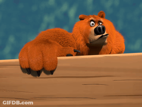 A Cartoon Bear Laying On A Wooden Table GIF
