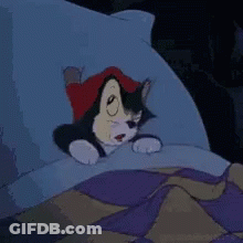 A Cartoon Cat Is Laying In A Bed With A Pillow . GIF