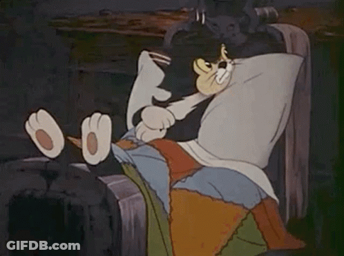 A Cartoon Cat Is Laying In A Bed With A Pillow On Its Head . GIF