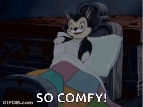 A Cartoon Cat Is Laying In A Bed With The Words `` So Comfy '' Written Below It . GIF