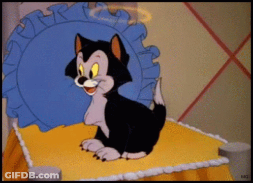 A Cartoon Cat Is Sitting On A Bed With A Blue Pillow Behind Him GIF
