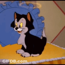 A Cartoon Cat Is Sitting On A Bed With A Blue Pillow Behind It GIF