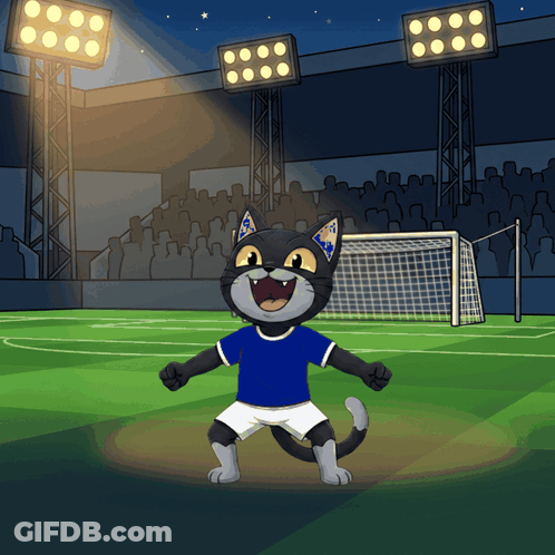 A Cartoon Cat Wearing A Blue Shirt And White Shorts Is Standing On A Soccer Field GIF