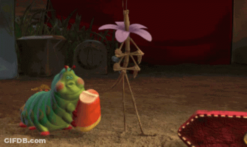 A Cartoon Caterpillar Is Holding A Candy Corn In Its Hand GIF
