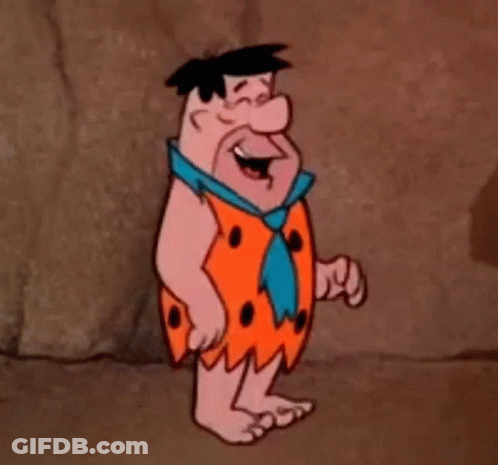 A Cartoon Character From The Flintstones Is Standing In Front Of A Rock Wall . GIF