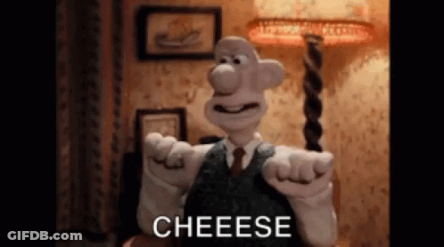 A Cartoon Character In A Suit And Tie Is Pointing At The Camera And Saying Cheese . GIF