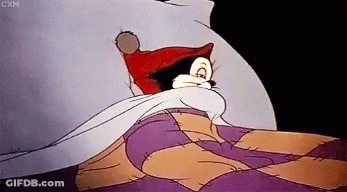 A Cartoon Character Is Laying In Bed With A Purple Blanket GIF